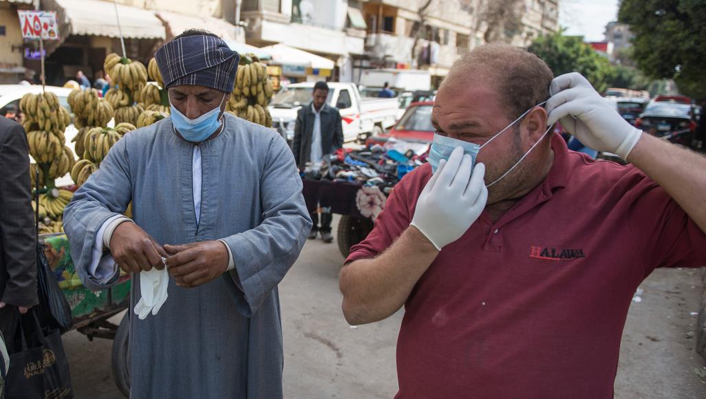 رجلان يرتديان أقنعة للوقاية من فيروس كورونا في أحد شوارع القاهرة (الأوروبية)