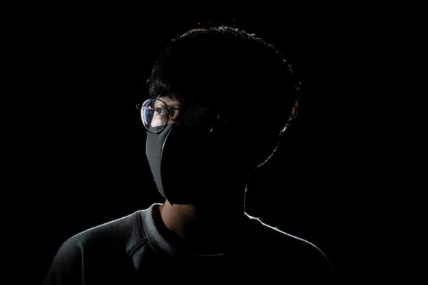 صورة لمتظاهر في هونغ كونغ نصف وجهه طوليا مظلم والنصف الآخر مضيء