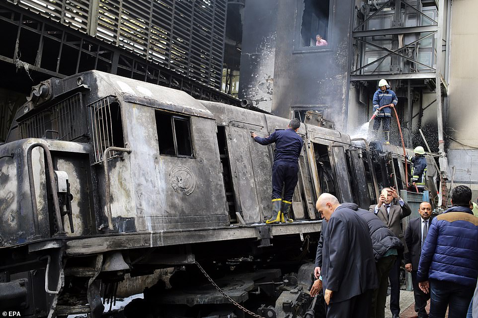 Firefighters extinguish flames and cool off a train engine after a fire broke out on tracks at the main train station in Cairo