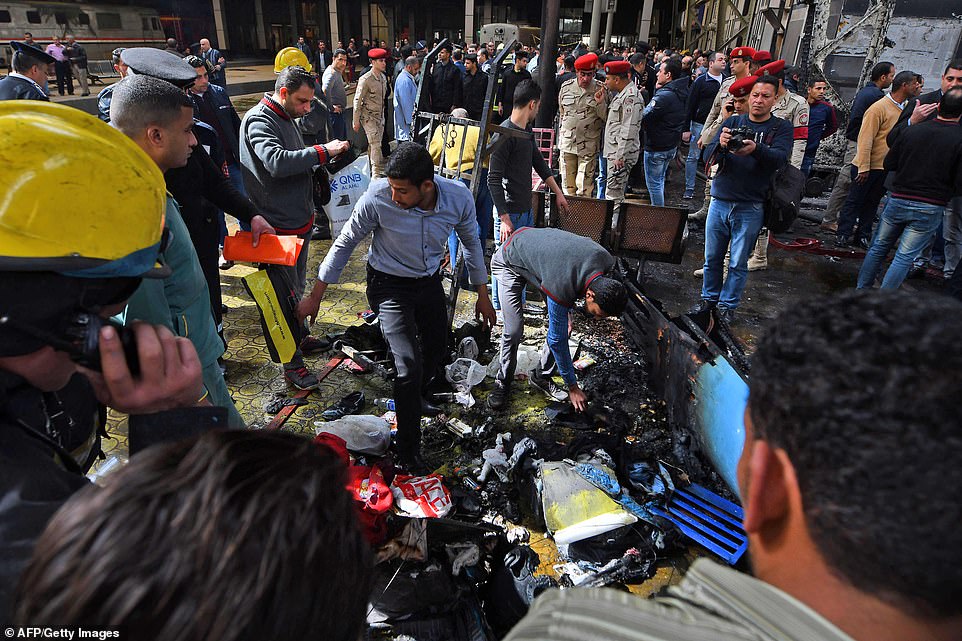 Members of the security forces and onlookers gather at the scene of a fiery train crash at the Egyptian capital Cairo's main railway station