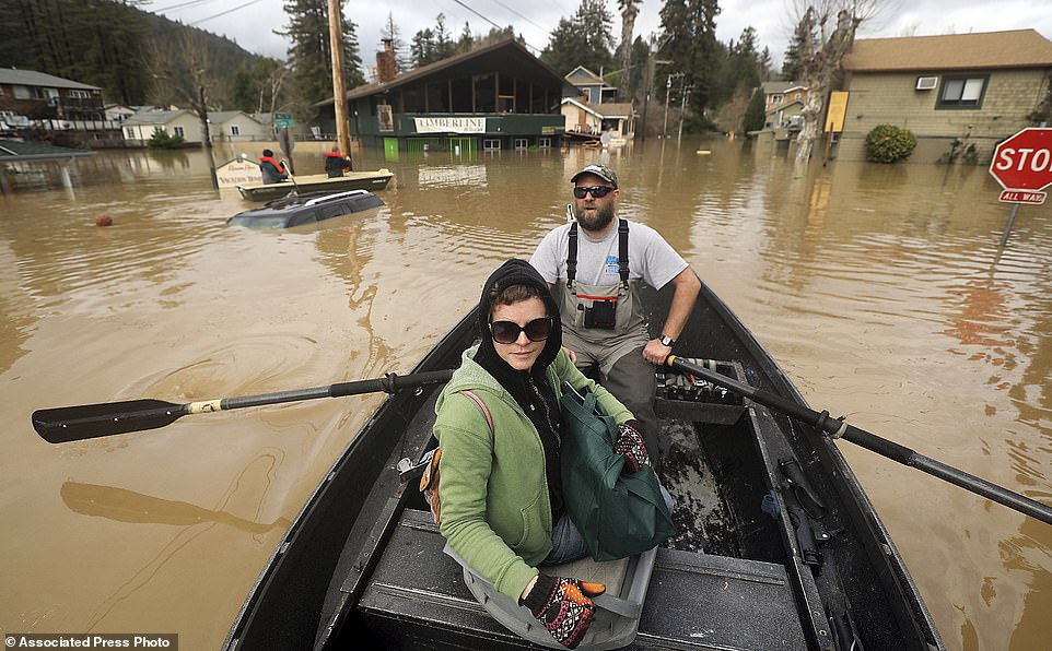 Scott Heemstra takes Veronica Burdette out of the flood zone as floodwaters rise along Mill Street in Guerneville