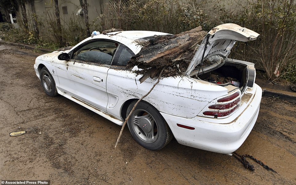 A Ford Mustang is covered in debris after being underwater during the flood after 3,700 people were ordered to evacuate