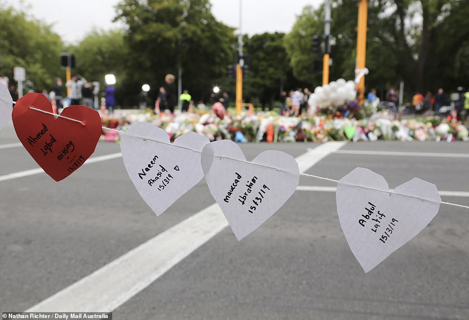 Relatives and friends write names of victims of the massacre on paper hearts and string them along the street of Christchurch
