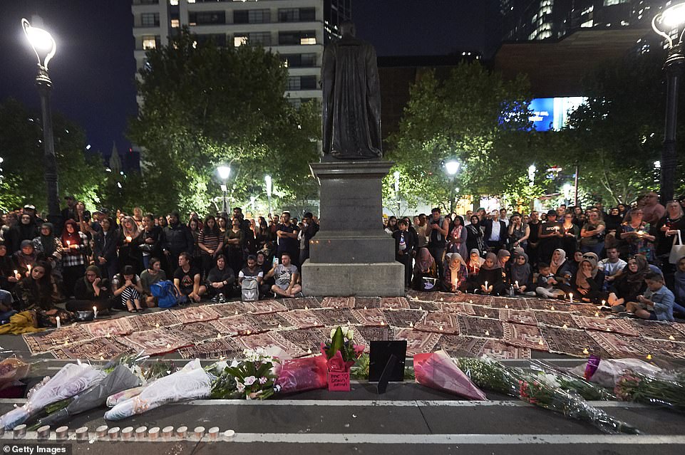 Flowers, candles and prayer mats strewn along the steps of the State Library of Victoria