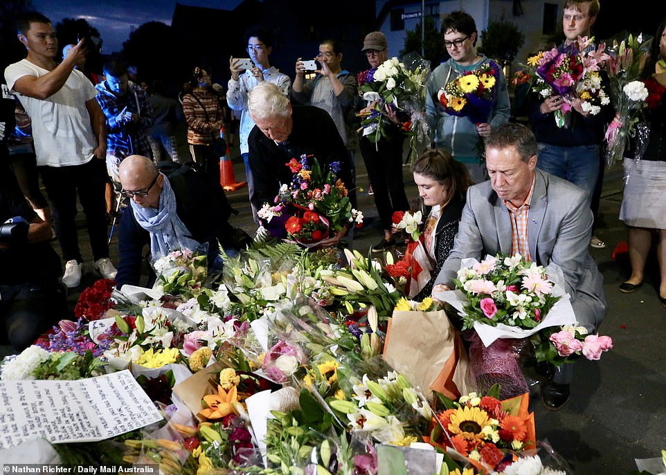 Members of the community move flowers closer to one of the mosques as part of a vigil after the attack yesterday