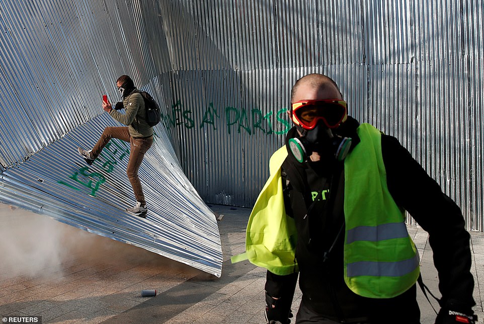 A protester wearing a yellow vest walks in front of demolished metal fencing during a demonstration by the "yellow vests" movement in Paris today