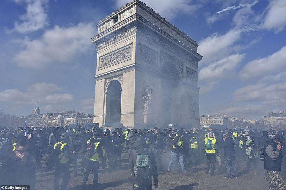 Protesters cover theirÂ faces and disperse momentarily after tear gas is fired into the crowd nearÂ Champs Elysees