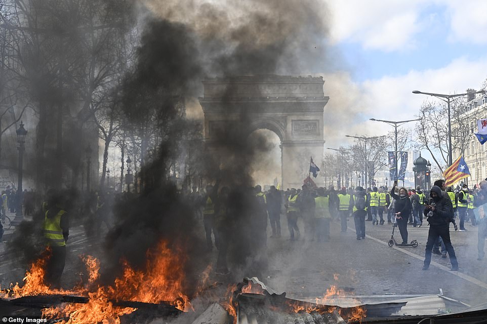 Yellow vests protesters setup a barricade using fire during by avenue Champs Elysees in Paris today