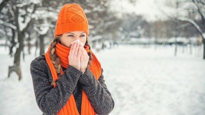 امرأة ترتدي ملابس الشتاء وتحيط أنفها بمنديل