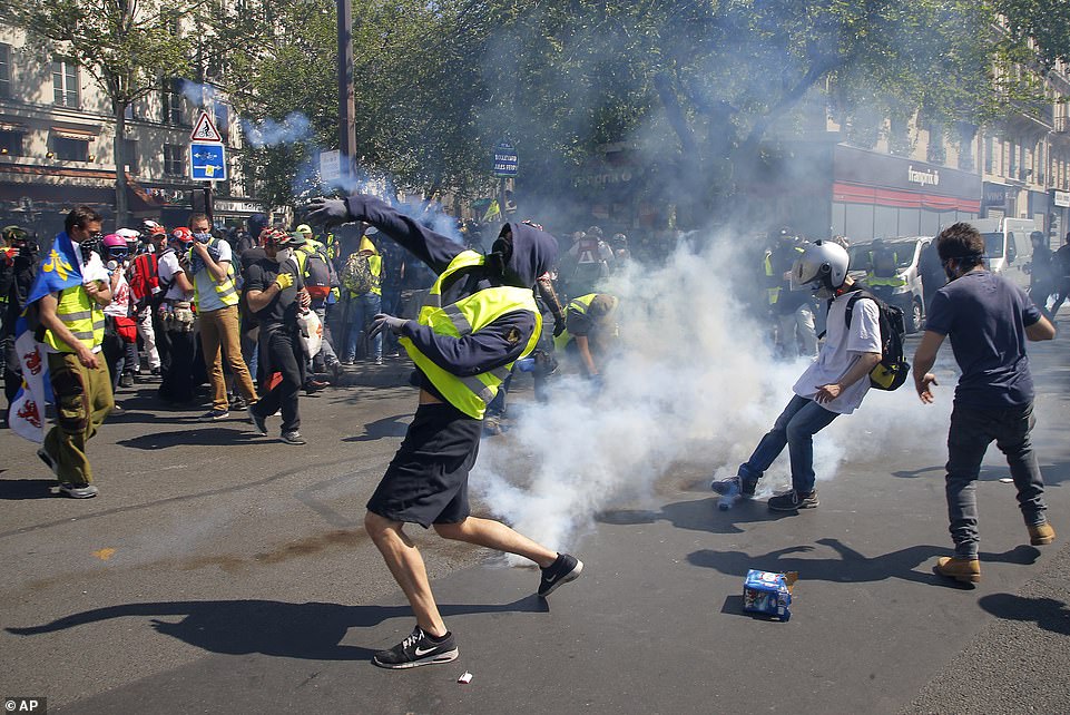 A demonstrator throws back a tear gas canister during today's Paris demonstration