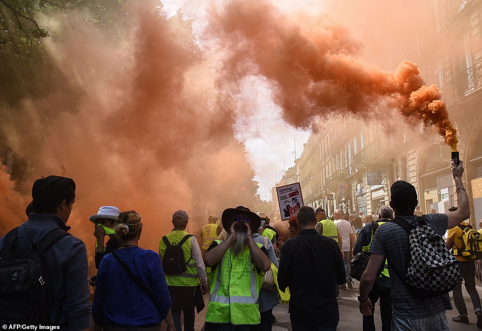 A protester shouts as another holds up a burning smoke flare during an anti-government demonstration in Bordeaux, southwestern France