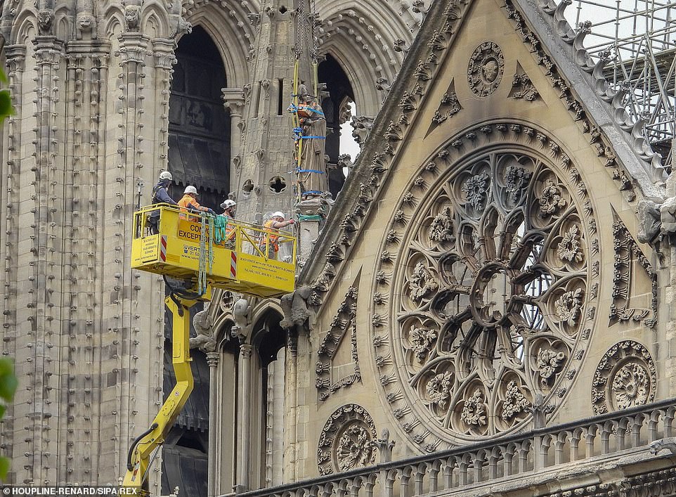 Workers stand on the roof of the Notre-Dame de Paris cathedral in Paris one week after a fire devastated the cathedral