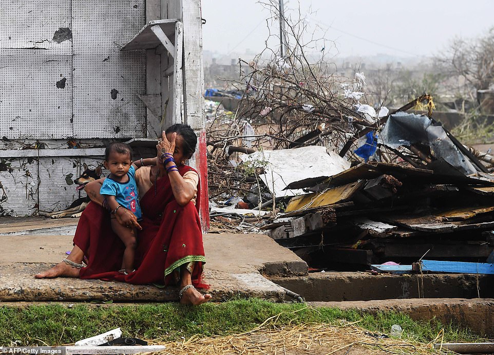 An Indian woman sits with her child next to storm-damaged buildings in Puri in the eastern Indian state of Odisha today after Cyclone Fani swept through the area