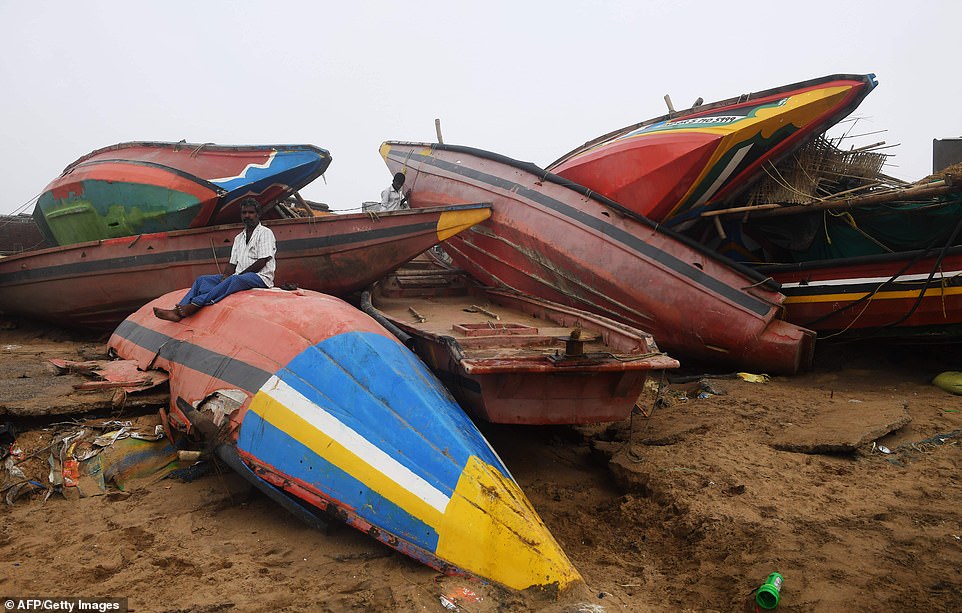 An Indian man sits on a damaged fishing boat along the seafront in Puri in the eastern Indian state of Odisha, many fishermen will have lost their livelihoods following the destruction