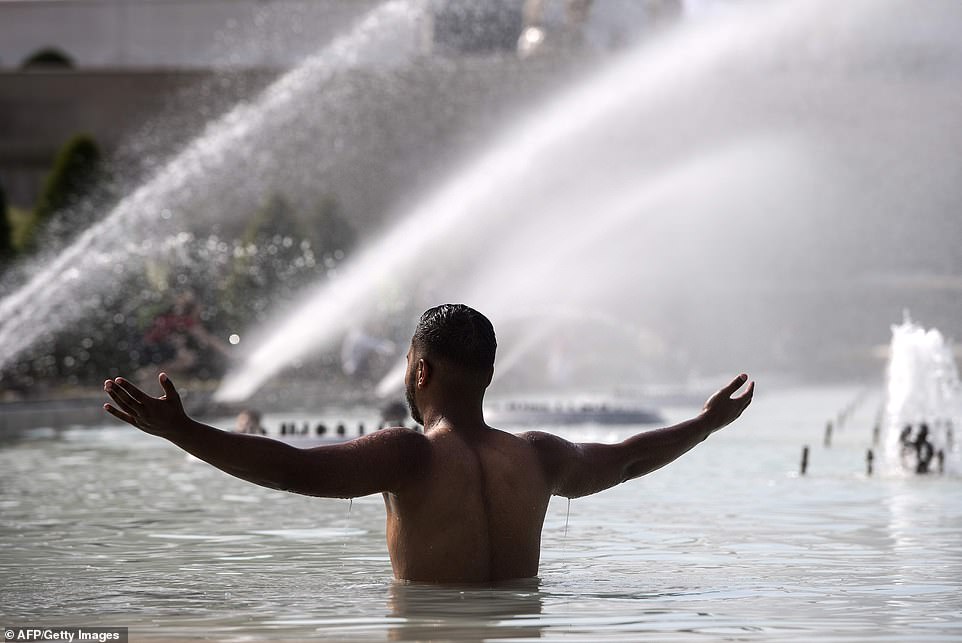 A man cools himself down in a pond at the Trocadero esplanade in Paris where orange warnings are issued
