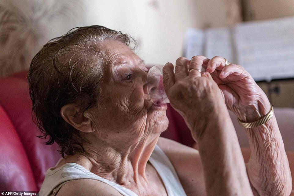 An elderly person drinking a glass of water to avoid heatstroke in Clermont-Ferrand, France