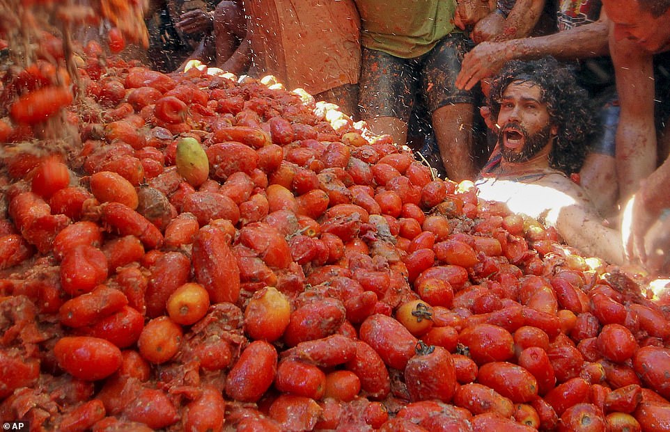 A man, with a look of panic plastered on his face, stares at a huge pile of tomatoes that are ready and waiting to be thrown by revellers