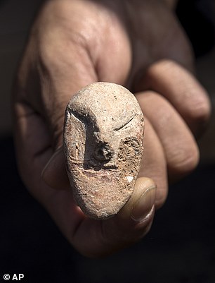 An archaeologist shows figurines found at the site