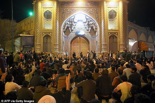 People gather outside the closed doors of the Fatima Masumeh shrine in Iran's holy city of Qom on Monday night