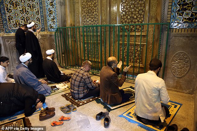 A group of worshippers pictured praying behind the closed doors of the Fatima Masumeh shrine in Qom, Iran's holy city, after it was shut due to fears over coronavirus which has continued to spread through the country