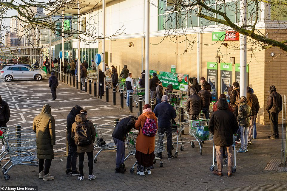 A huge queue of people is seen queueing outside an Asda in Middlesex while people continue to panic buy amid the coronavirus pandemic