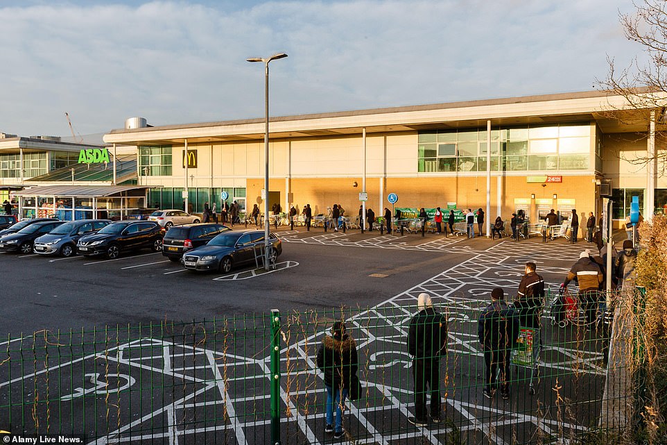 A huge queue of people is seen snaking round the carpark of an Asda in Middlesex while people continue to panic buy amid the coronavirus pandemic