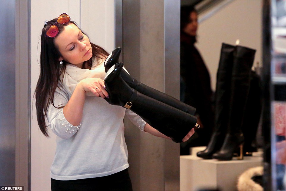MANHATTAN: A woman looks at a pair of boots in Macy's Herald Square, which is offering 40 per cent off of boots and shoes 