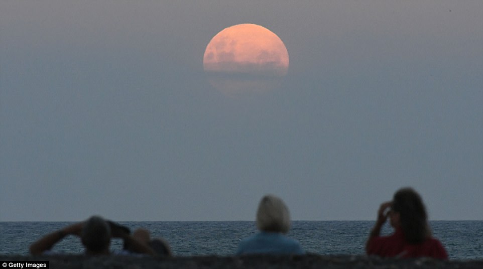 Dr Daniel Brown an astronomy expert from Nottingham Trent University told MailOnline that when the moon is quite low in the horizon the atmosphere of the earth will redden it independent of eclipse. Crowds gather on the Marine Parade Beach to watch the full moon rise just hours before the rare super blue blood moon 