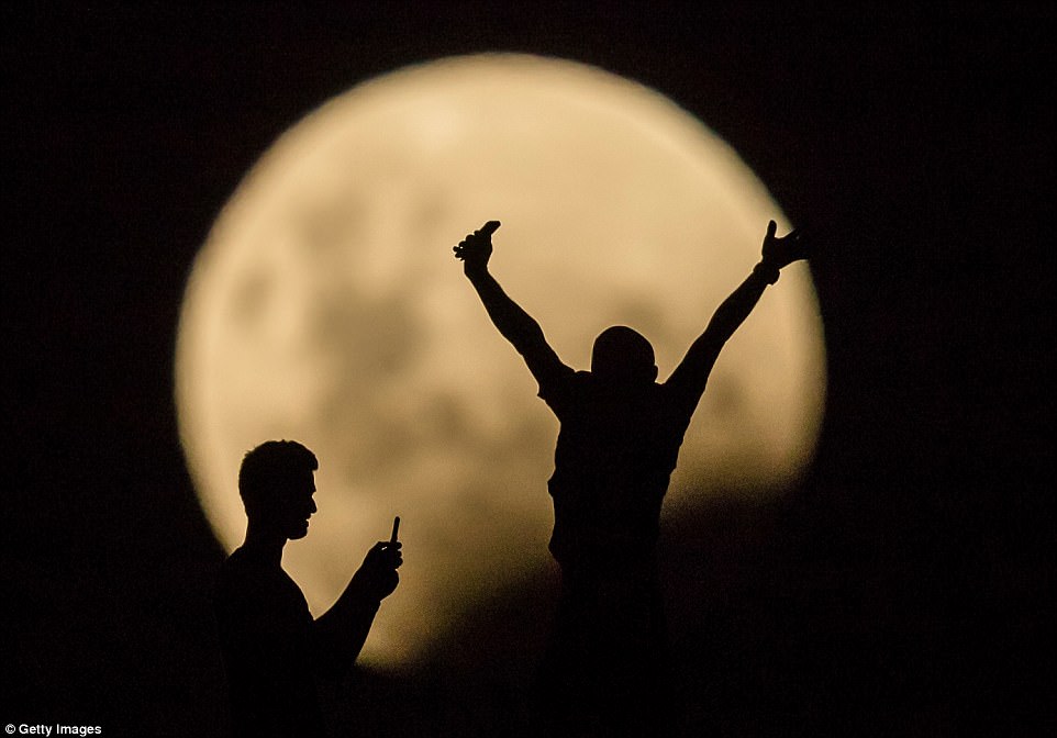 People take photos of the super moon in Lancelin, Australia. Not only is it the second full moon in January, but the moon will also be close to its nearest point to Earth on its orbit, and be totally eclipsed by the Earth's shadow