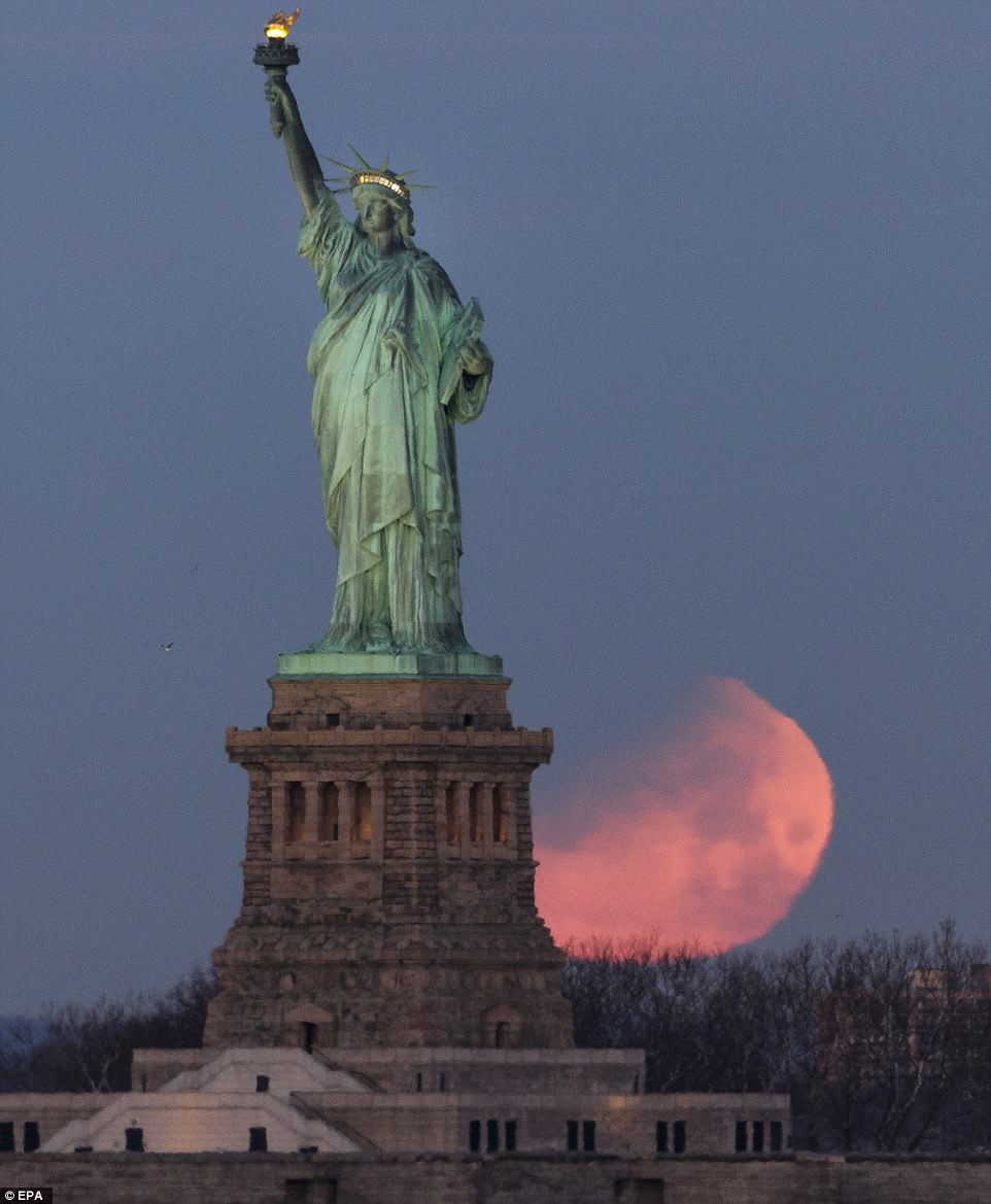 The moon sets behind the Statue of Liberty in New York. . This is the last one in a series of three consecutive 'Supermoons', dubbed the 'Supermoon Trilogy'