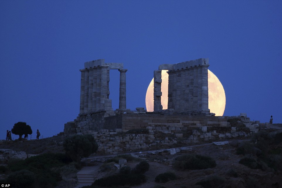 The 'Blood Moon' rises behind the ancient Temple of Poseidon in cape Souni 40 miles south of Athens in Greece on Friday 