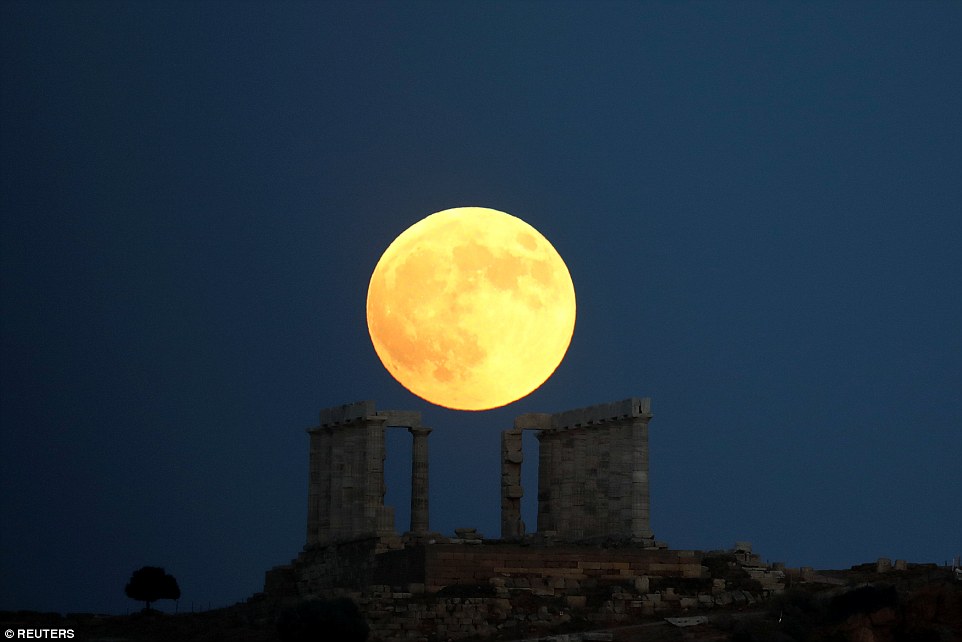 Once in a lifetime: The 'Blood Moon' rises above the Temple of Poseidon near Athens, Greece as the sky darkens this evening