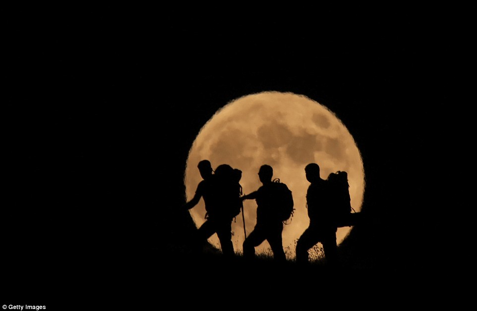 Three men in the moon: Walkers are pictured hiking up Mount Artos in Turkey as the Blood Moon dazzles behind them 