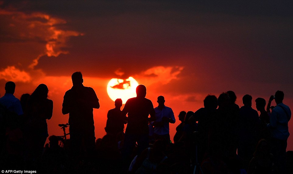 Red sky: People gather to witness the lunar eclipse as the sky turns red across Berlin, Germany on Friday evening 