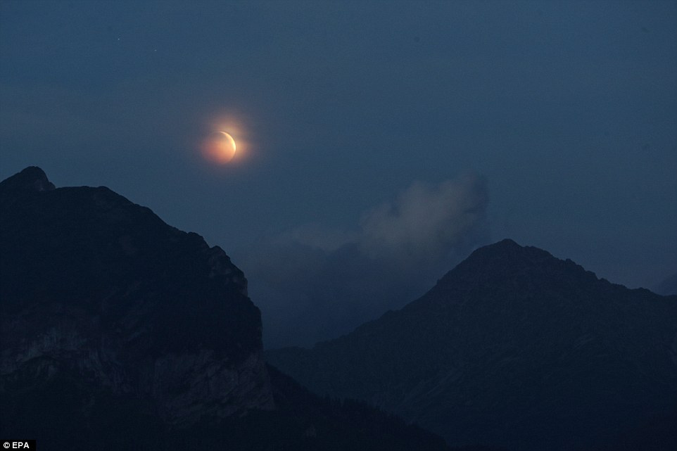 Clouds aren't ruining the Blood Moon for people in Poland as the crimson ball is pictured above the mountains in Zakopane