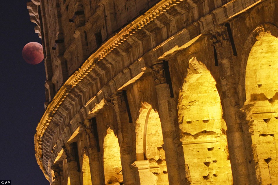 Blood Moon rises: The Colosseum in Rome is pictured with a crimson moon late on Friday night as the lunar eclipse happens 