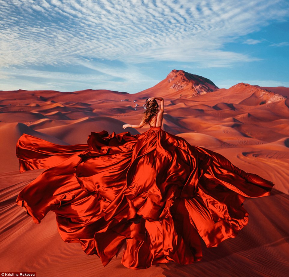 This model's stunning red gown blows in the breeze and blends in with the red sand of the Rub Al Khali Desert in Oman