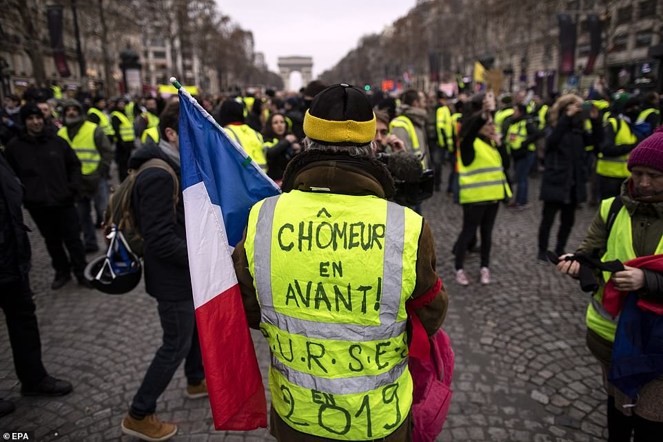 A protester wears a yellow vest with a slogan reading 'unemployed walk' during a 'Yellow Vests' protest march on the Champs Elysees boulevard, in Paris