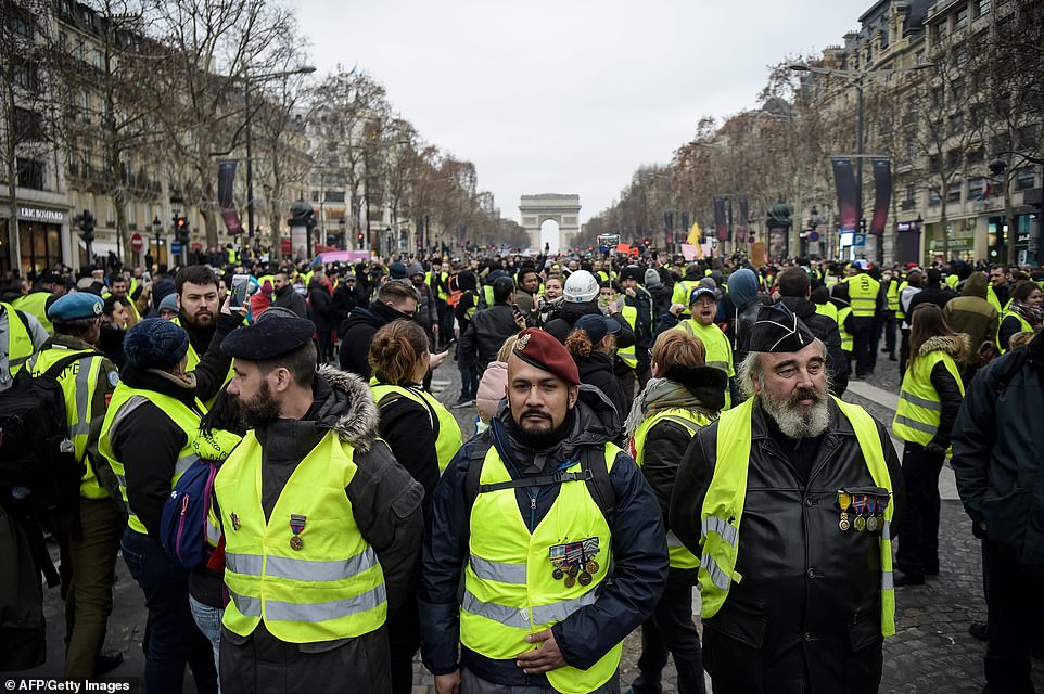 The 'yellow vest' demonstrations - named after the high-visibility jackets worn by the protesters - began in rural France in November over increased fuel taxes. Men wearing campaign medals and yellow vests stand on The Champs-Elysees in Paris today