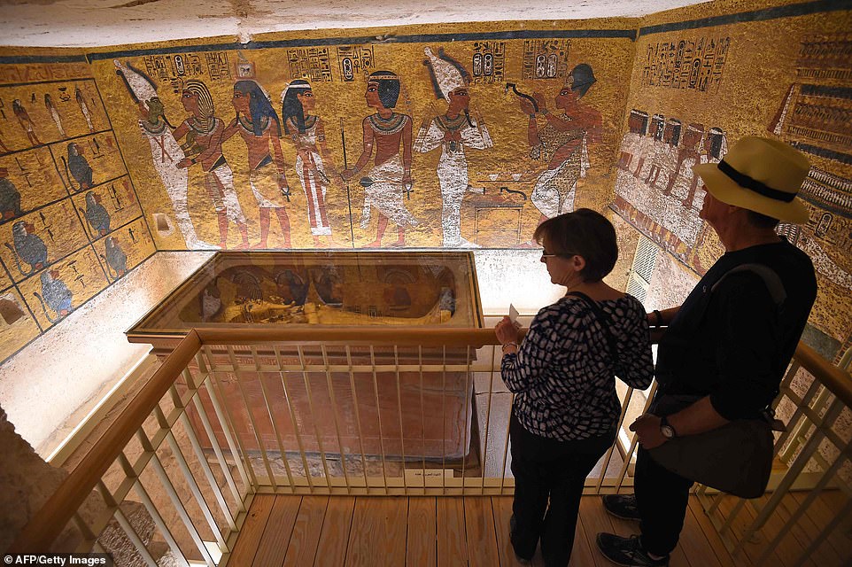 A man and woman look at the golden sarcophagus of the famed Egyptian ruler, after the years of conservation work on his tomb