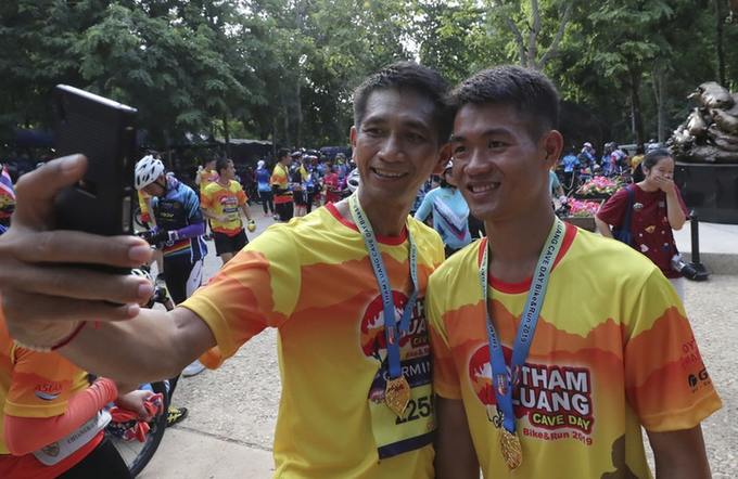 A runner takes a selfie with former football coach Ekkapol Chanthawong, right