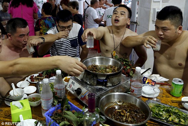 Cheers!: Festival-goers settle down to dishes of dog meat at the notorious Yulin festival, where as many as 10,000 dogs are being skinned alive, butchered and eaten