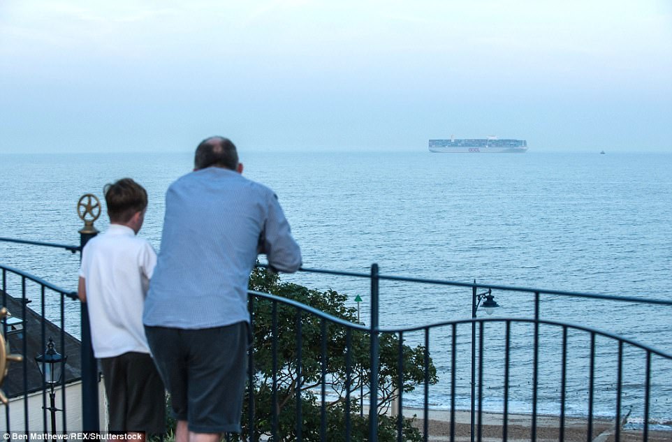 Eyes on the horizon: A man and boy look on in awe at the giant vessel floating through the sea