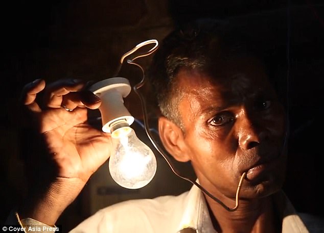 Great stunt: Mr Kumar is seen letting the electricity to power a bulb run through his mouth